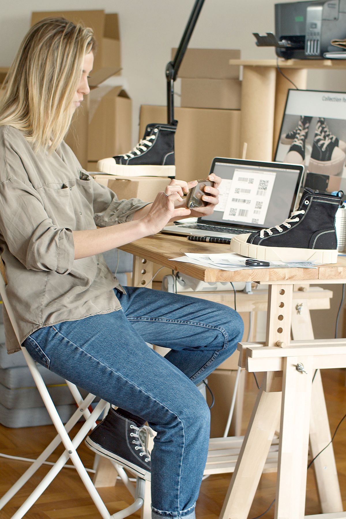 Vendeuse photographiant une chaussure avec son téléphone pour préparer une annonce